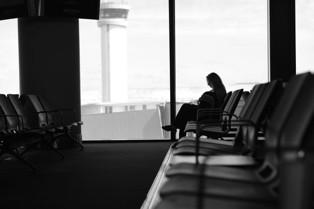 Osoba sedi u aerodromskoj čekaonici pored velikog prozora